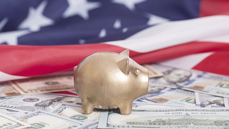 piggy bank  on money in front of american flag