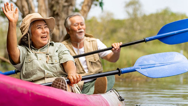 Retired couple have fun canoeing together in a lake.