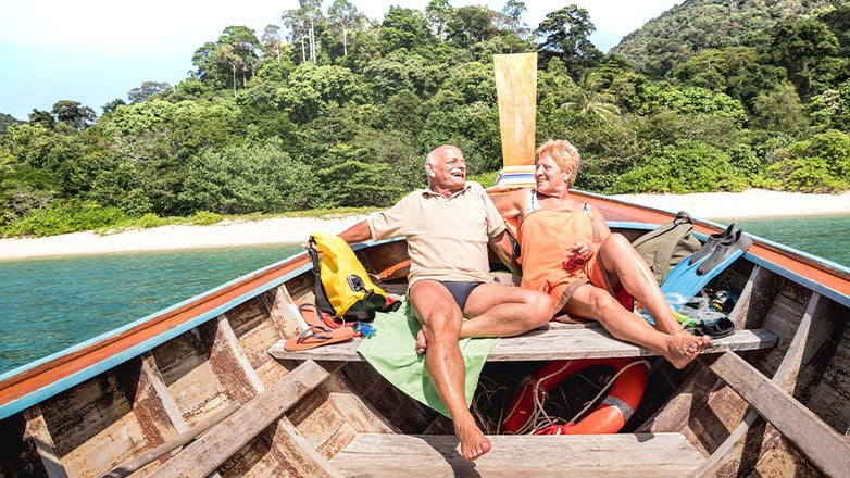 couple sitting in wooden boat off cost of beach