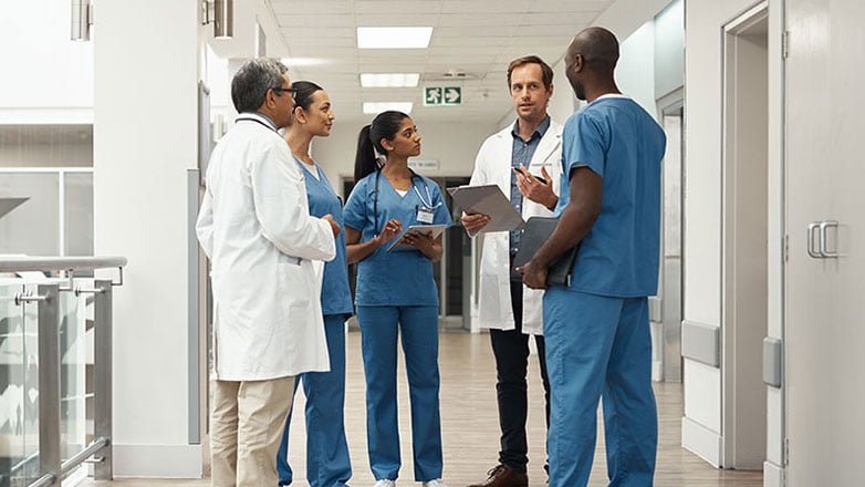 Hospital staff meets in the hallway to discuss their agenda for the day.