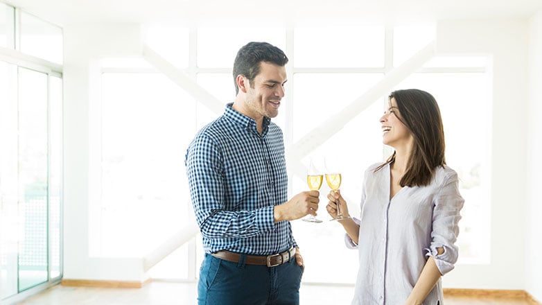 Couple celebrating with champagne in an empty house.
