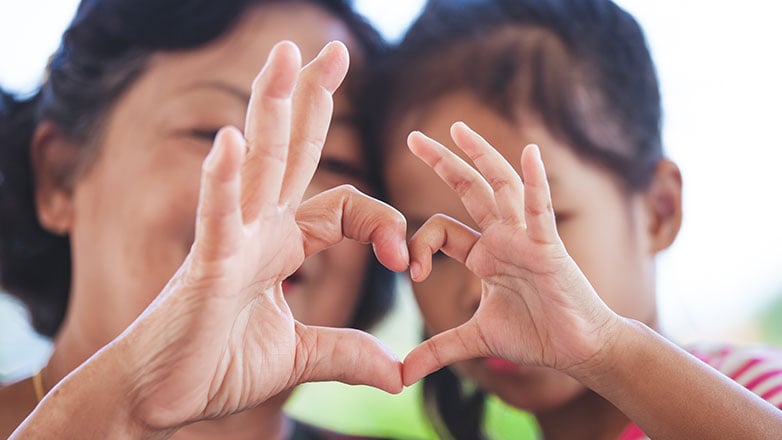 Mom and daughter put their hands together to make a heart.