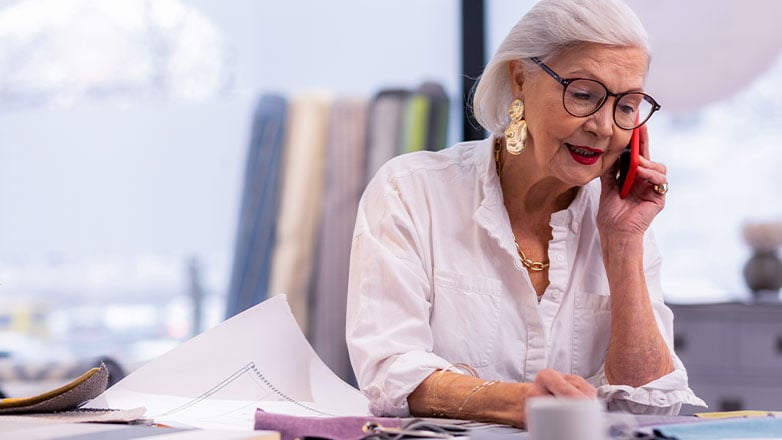older woman on phone doing professional work at desk