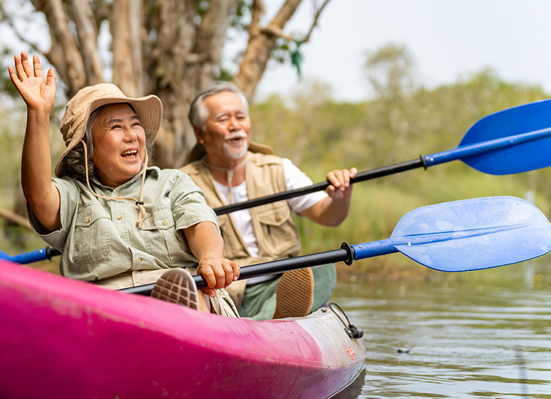 Retired couple have fun canoeing together in a lake.
