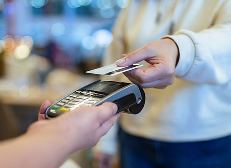 Customer uses their debit card at a contactless card reader in a store.